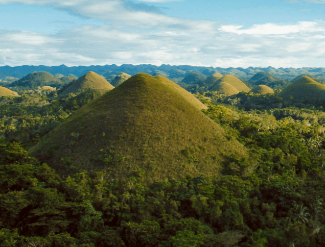 A Scenic aerial view of Chocolate Hills under a clear blue sky.