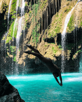 A photo of a tourist jumping into the waters of Pahangog Falls